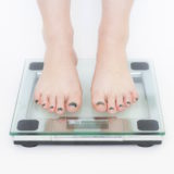 正月太りが気になって体重計にのるイメージ